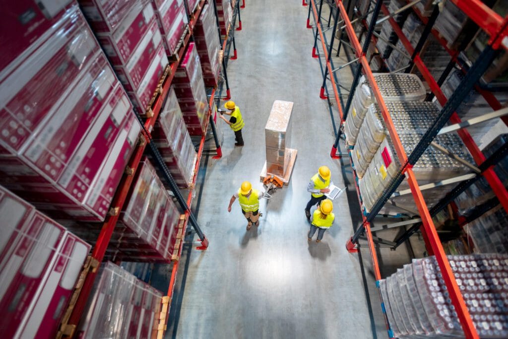 TXG warehouse staff picking orders between racking aisles of packed cartons